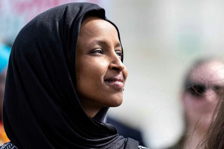 A woman wearing a black hijab looking thoughtfully into the distance