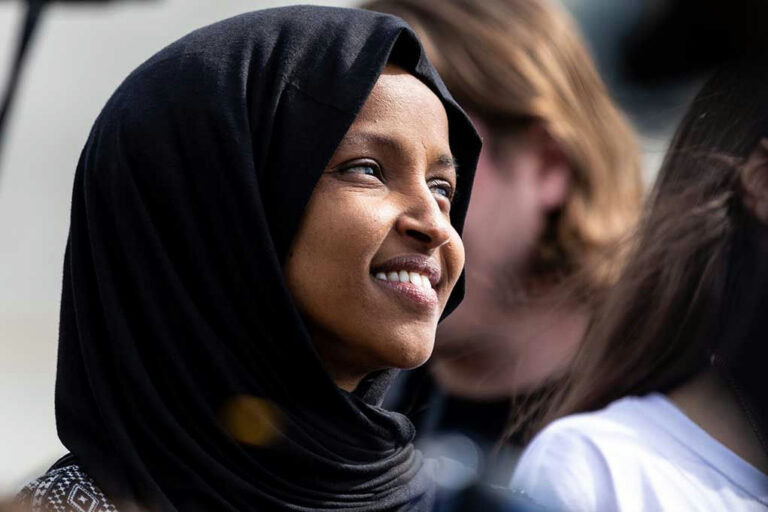 Woman in a headscarf smiling outdoors.