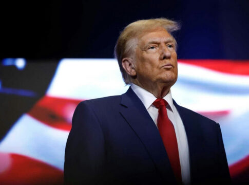 donald trump in suit with red tie American flag backdrop