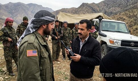A military personnel and a local leader engaged in conversation in a mountainous region