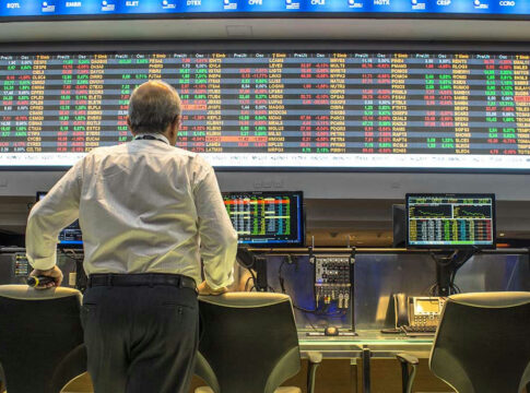 Person viewing stock market data on multiple screens.