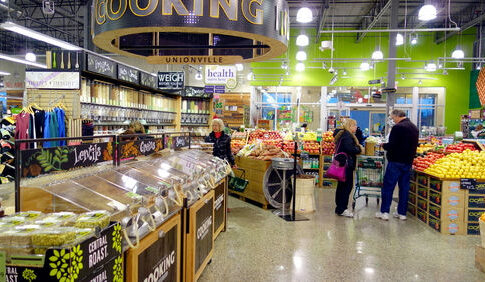 People shopping in a grocery store produce section.