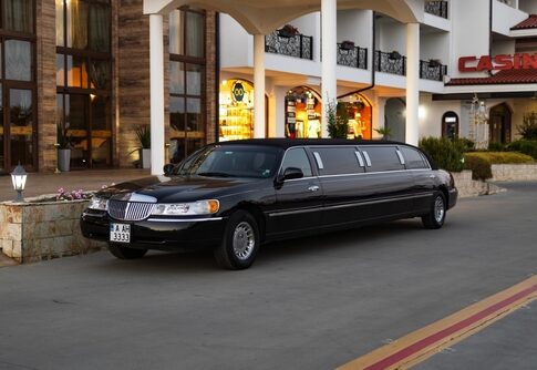 A black limousine parked in front of a modern building with a casino sign